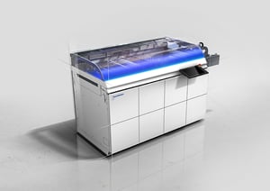 Hunkeler GEN8 EVO – Modulares Digitaldruck-Finishing-System mit innovativem Industrial Design von Alphagate. Die transparente Schnittansicht zeigt die Verarbeitungstechnik, während das blaue Licht den laufenden Betrieb signalisiert.