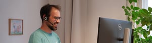 A smiling colleague at his workstation while having a conversation.