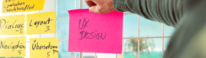 UX Design in Automation Technology: A person is attaching a Post-it with 'UX Design' to a planning board in order to develop user-friendly software solutions for mechanical engineering.