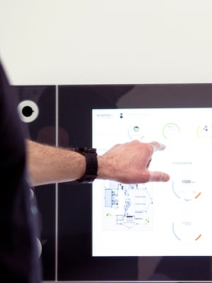 Person operating an industrial touch display with a graphical user interface showing production data from esmo automation.